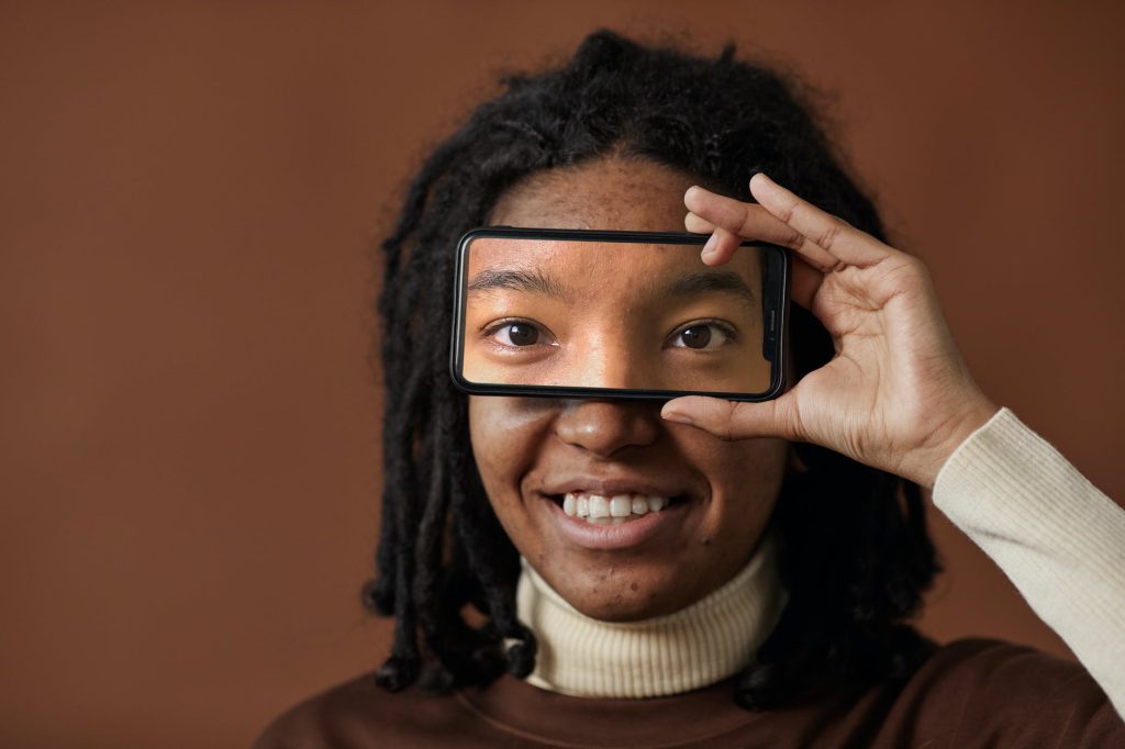 a woman holding black smartphone with eyes picture on screen